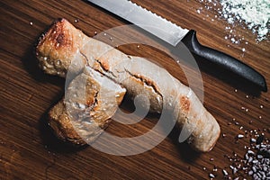 Two pieces of bread, white flour, water, seeds and a knife on the table