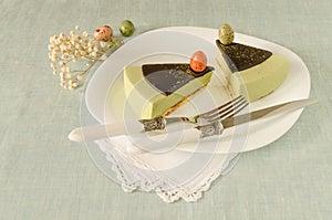 Two pieces of easter cake with tea matcha decorated chocolate ganache and sweet-stuff eggs on white plate