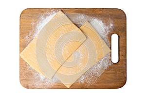 Two pieces of frozen puff pastry on a cutting board, top view. Isolate on a white background