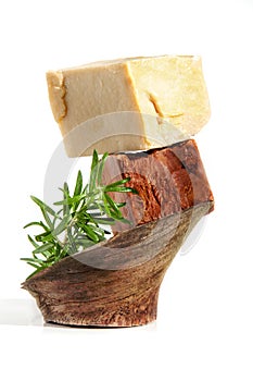 Two pieces of handmade coffee chocolate olive and herbs soap with rosemary on wood isolated on white