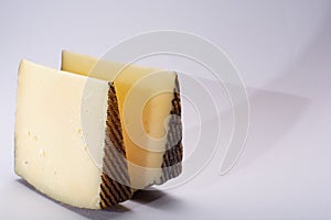 Two pieces of Manchego, queso manchego, cheese made in La Mancha region of Spain from the milk of sheep of the manchega breed, is photo