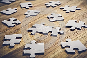 Two pieces of a puzzle connected on a wooden table with many other pieces of the puzzle. Problem Solving Concept