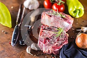 Two pieces raw beef shank and basic ingredients on goulash - onion pepper tomatoes garlic salt spices and rosemary