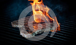 Two pieces of Striploin beef tips on getting grilled on a barbeque grill.GRILLING