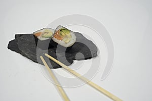 two pieces of sushi in a blackboard plate with chopstick, ginger and wasabi