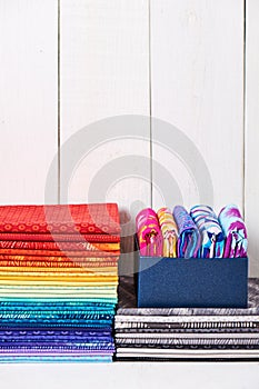 Two pile of pieces colorful quilting fabrics on white wooden background