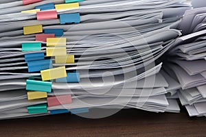 Two piles of documents with colorful clips on desk