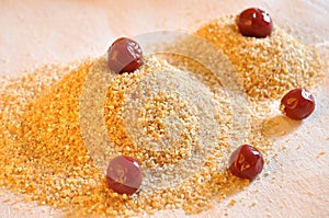 Two piles of wheat grain with canned cherries on the background of sackcloth