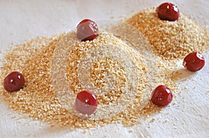 Two piles of wheat grain with canned cherries on the background of sackcloth