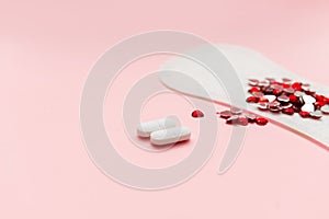 Two pills and menstruation pad with red hearst on it, painkiller contraception medication concept