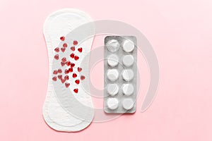 Two pills and menstruation pad with red hearst on it, painkiller contraception medication concept