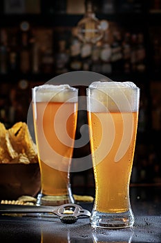 Two Pilsner Glasses with Beer on Bar