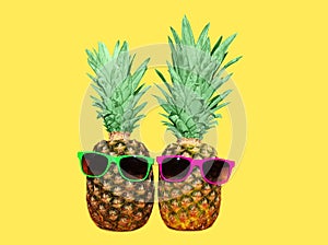 Two pineapple with sunglasses on yellow background