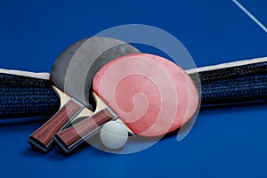 Two ping pong rackets. Table tennis rackets and a ball on a blue tennis table