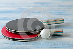 Two ping pong rackets. Table tennis rackets and a ball on a blue wooden table. sport game