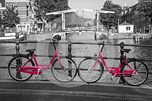 Two pink bikes on the bridge over the channel in Amsterdam