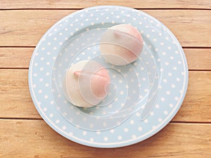 Two pink birthday peach buns on a blue plate. pastel tone.