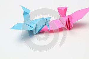 Two pink and blue paper birds, folded origami art.