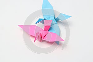 Two pink and blue paper birds, folded origami art.