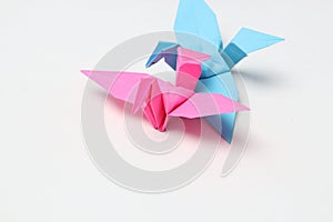 Two pink and blue paper birds, folded origami art.
