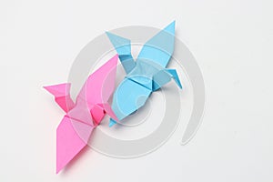 Two pink and blue paper birds, folded origami art.