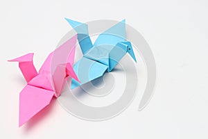 Two pink and blue paper birds, folded origami art.