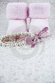 Two pink booties for babies with several bracelets