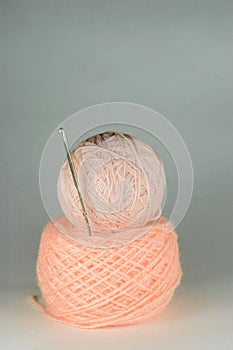 Two pink coils of yarn and crochet hook.