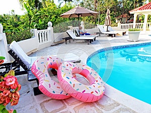 Two Pink Float Rings At The Edge of a Swimming Pool