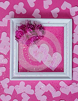 Two pink harts that say you and me are in the frame with flowers