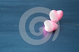 Two pink hearts on dark blue or silver on wooden or metal background. Valentine`s Day