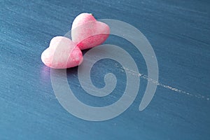 Two pink hearts on dark blue or silver on wooden or metal background. Valentine's Day