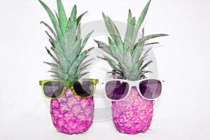 Two pink pineapple in sunglasses on a white background.