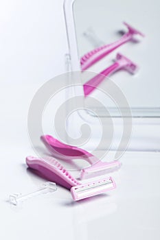 Two pink razor front of a mirror