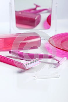 Two pink razor on white table front of a shower gel