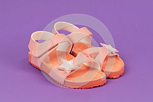 Two pink sandals on purple background. Cute pink sandals for little girl