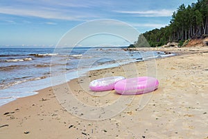 Two pink swim rings on sandy beach