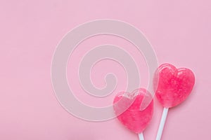 Two Pink Valentine`s day heart shape lollipop candy on empty pastel pink paper background. Love Concept. top view.