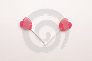 Two Pink Valentine`s day heart shape lollipop candy on empty white paper background. hipster Minimal Love Concept. top view.