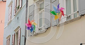 Two pinwheels spin and stop spinning outside windows with wooden shutters - heatwave concept.