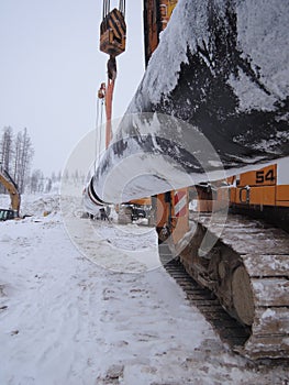 Two pipelayers move a pipe