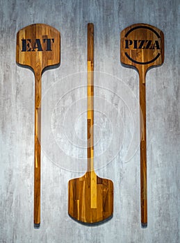 Two pizza paddle with text `eat` and `pizza` hang on wall for background