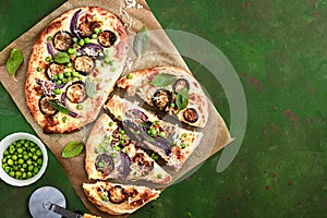 Two pizzas with eggplant, green peas and red onion, top view