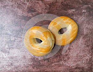 Two plain bagels on a red mottled countertop top view