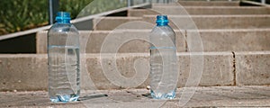 Two plastic bottles of clean drinking water on the road, source of life. Banner