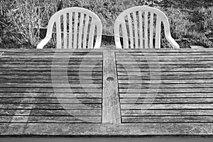 Two plastic chairs and a wooden table in the vegetable garden