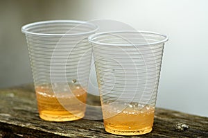 Two plastic cups with beer on wooden plank