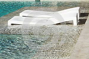 Two plastic deck chairs in a swimming pool