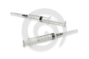 Two plastic disposable syringes with a needle in the cap