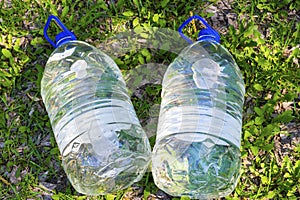 Two plastic water bottles on the grass.